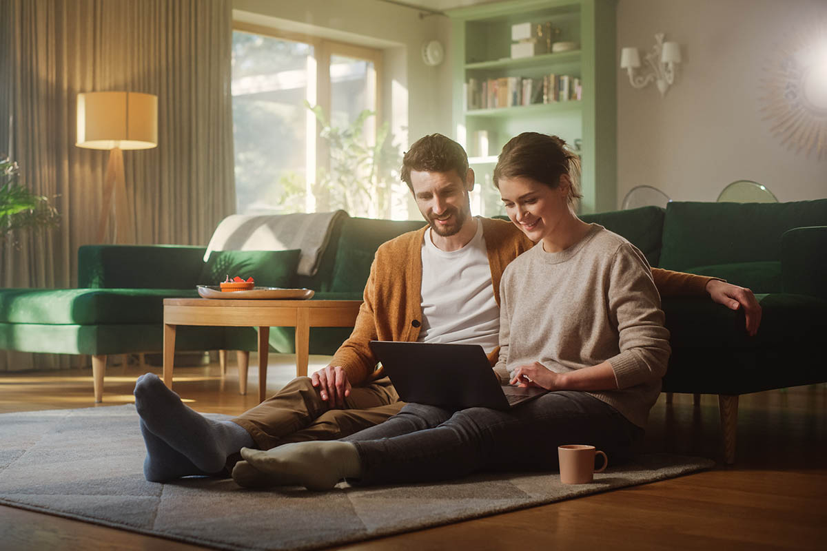 Couple Use Laptop Computer, while Sitting on the Living Floor